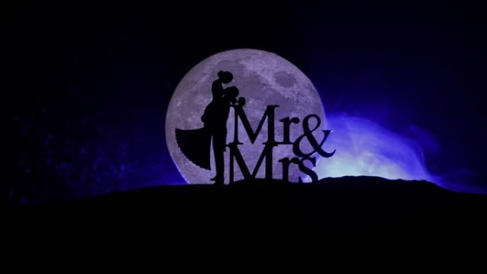 一对有星空和月球背景的夫妇的剪影。夜晚月光下的幸福夫妻。创意艺术品餐桌装饰。