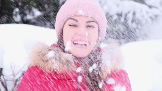 一个开朗的年轻女子在冬季散步时扔雪，并在飘落的雪中欢欣鼓舞。