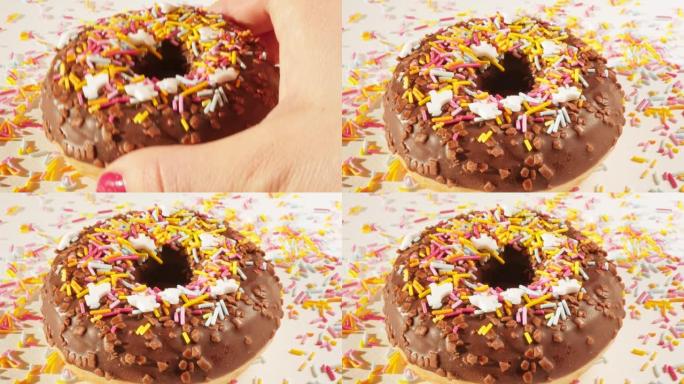 手推美味巧克力甜甜圈，糖彩虹洒在白色盘子上