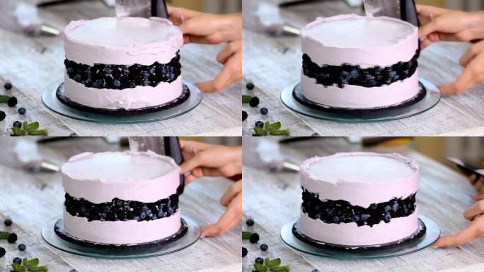 糖果用锅铲在饼干蛋糕上抚平紫色奶油。自制糕点的概念，烹饪蛋糕