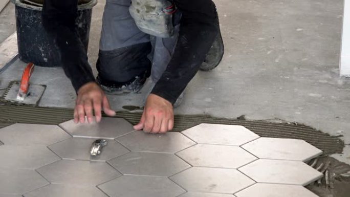 工人在地板上铺设六角形石材瓷砖。
