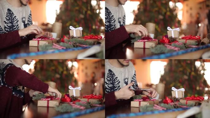 人的双手在圣诞节礼物上系弓的近距离观察。在新年树附近的家中，在木桌上添加杉木树枝，圆锥体，甘蔗糖果的