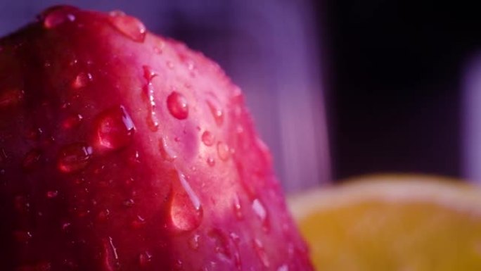 大滴水滴落在红色成熟的苹果上，并滚落在皮肤上。