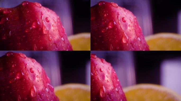 大滴水滴落在红色成熟的苹果上，并滚落在皮肤上。