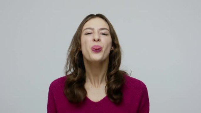穿着套头衫的有趣顽皮漂亮的黑发女人伸出舌头，玩得很开心
