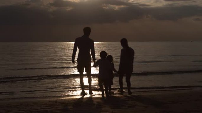 快乐的亚洲家庭奔跑的剪影，在日落的夜晚一起在海滩上放松度假，父母和孩子快乐休闲，夏天有日出的热带乐趣