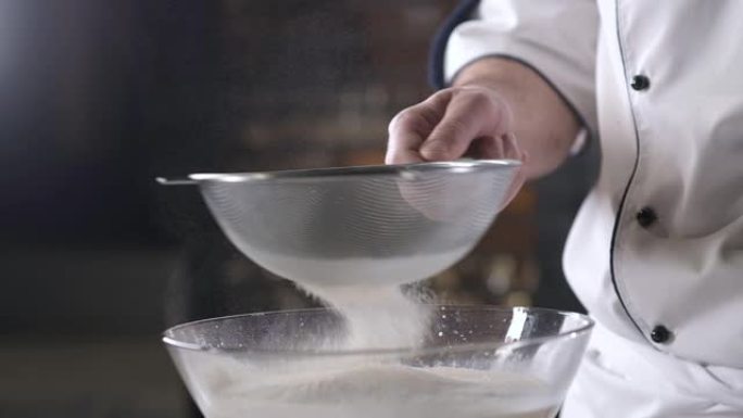 男人的手通过烘焙筛筛面粉。