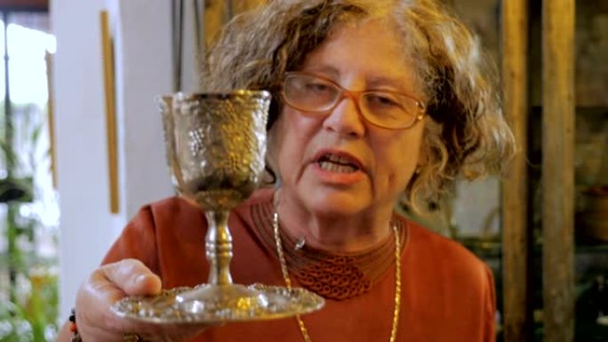 一位有吸引力的年长犹太妇女解释了kiddush杯