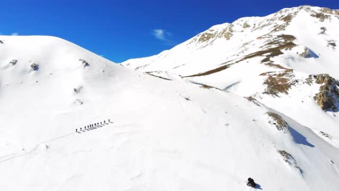 冬季高山登山队在高海拔山峰中连续行走的空中无人机镜头