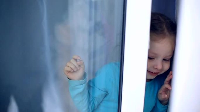 一个蓝眼睛的小女孩和她美丽的母亲坐在窗台上，冬天在乡间别墅里看着窗外