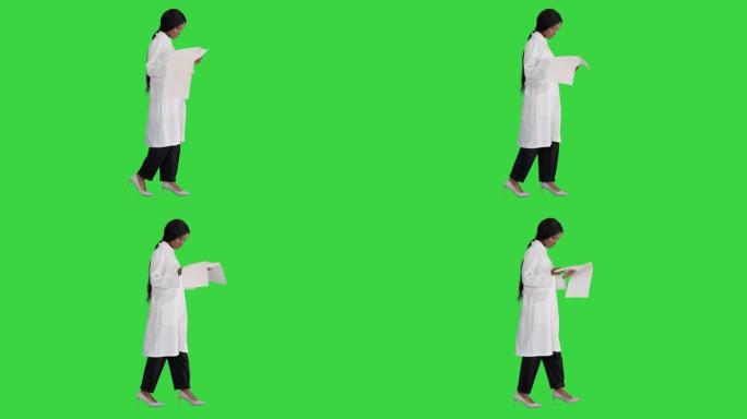 美国黑人医生妇女在绿色屏幕上行走并查看心电图记录，色度键