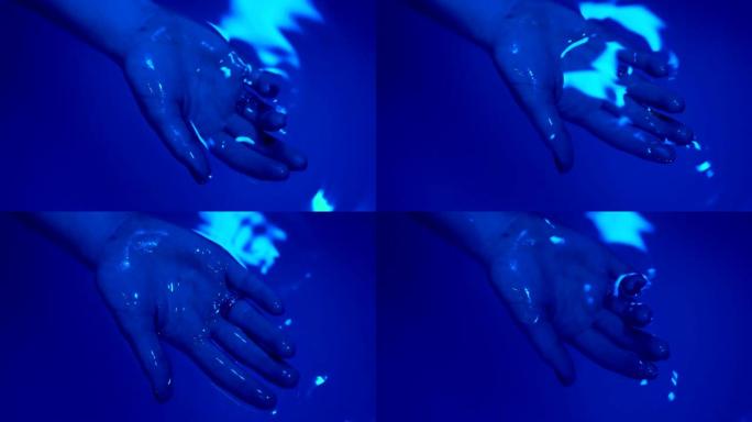 放松概念。一个年轻女子的手被握在水疗盆或水池的水面上，里面有海盐。超蓝镜头