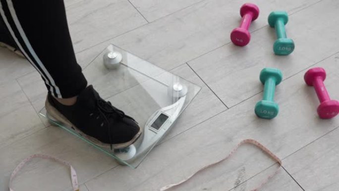 在健身室中，胖女人的腿在秤上称重以检查体重。加大码肥胖成熟女性概念