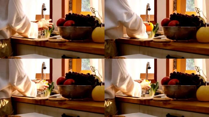 关闭女人的手在厨房里洗水果，光线透过窗户