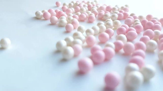 珍珠母白色和粉红色小球或化妆粉珠在白色背景上滚动，最小创意概念，4k视频