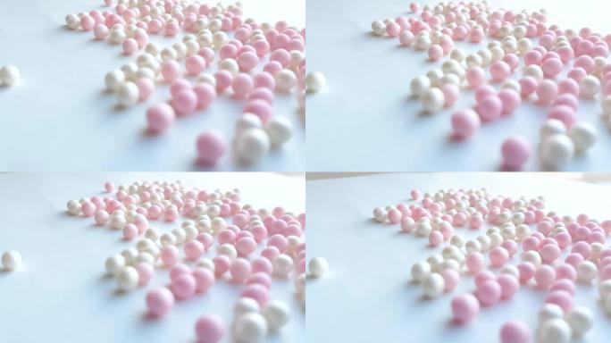 珍珠母白色和粉红色小球或化妆粉珠在白色背景上滚动，最小创意概念，4k视频