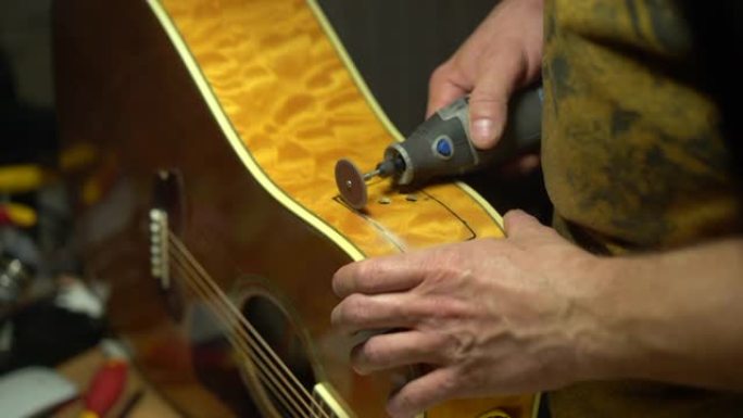 吉他大师正在他的工作室在灯下用特殊工具修理原声吉他。
