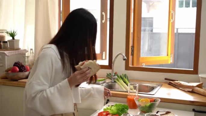 年轻的亚洲妇女拿起手机走出厨房。