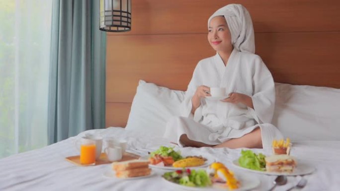 年轻的亚洲女性在床上享受早餐