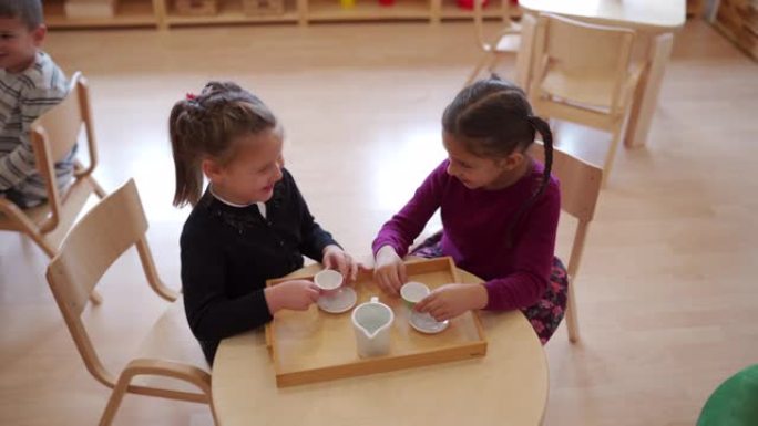 两个可爱的女孩在幼儿园举行茶会