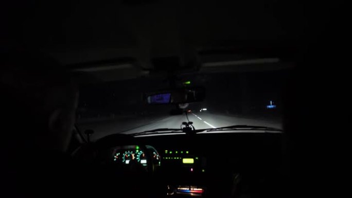 司机晚上在灯火通明的道路上骑车。汽车破裂并摇晃。内部视图。