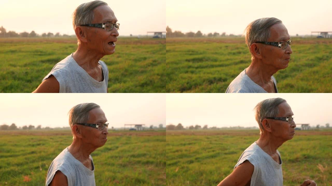 亚洲高级男子在日落背景下在乡村的田野上慢跑。医疗保健概念。
