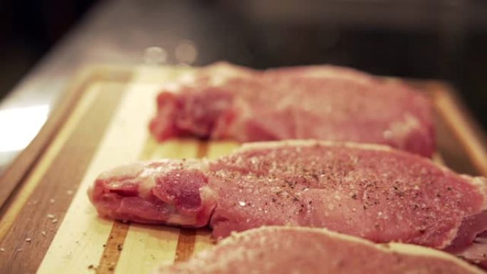 在准备烧烤的木制切菜板上新鲜的调味未煮熟的生去骨里脊肉猪排的慢动作移动镜头