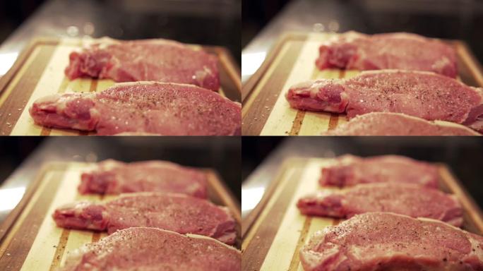 在准备烧烤的木制切菜板上新鲜的调味未煮熟的生去骨里脊肉猪排的慢动作移动镜头