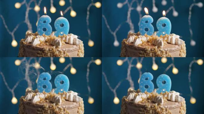 蓝色背景上有69号蜡烛的生日蛋糕。蜡烛吹灭了。慢动作和特写视图