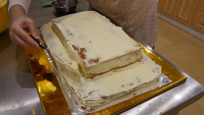 女糕点师用糖霜装饰一个大蛋糕。特写