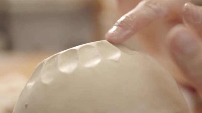 女性陶工的手在湿粘土容器上平滑切口图案