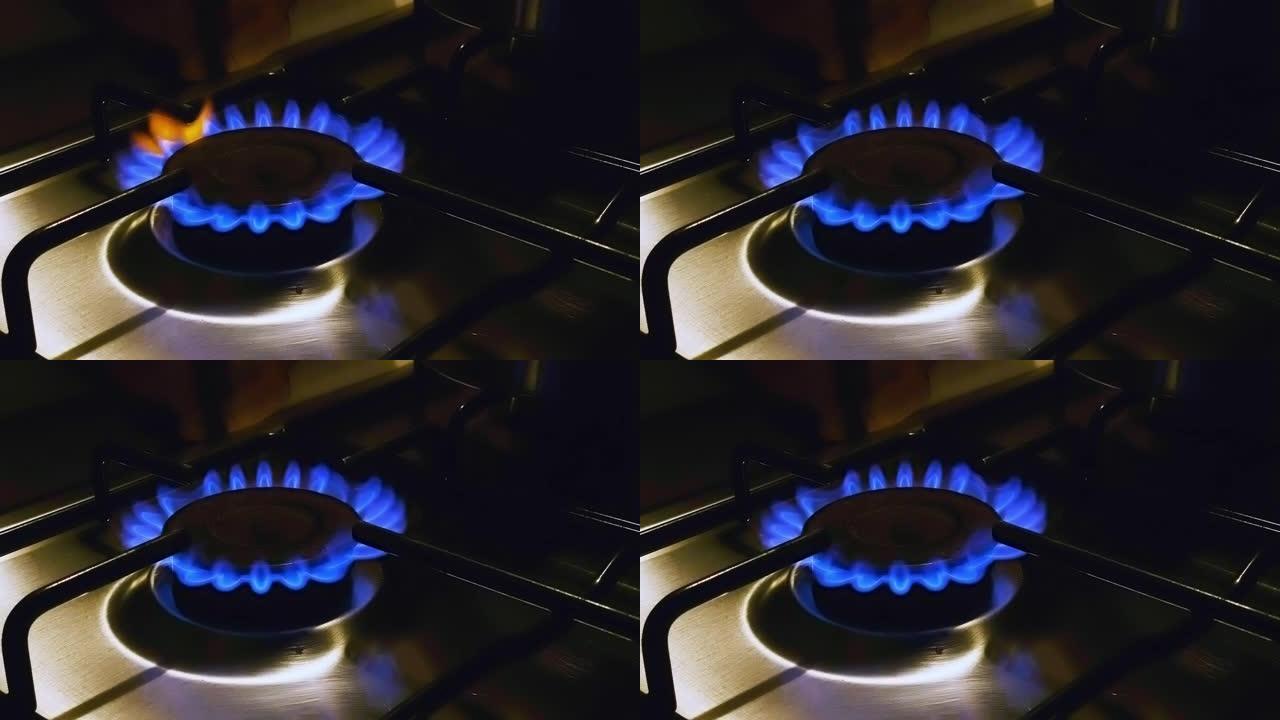 在弱光下在家用厨房中点亮的炉子的蓝色火焰的特写视图