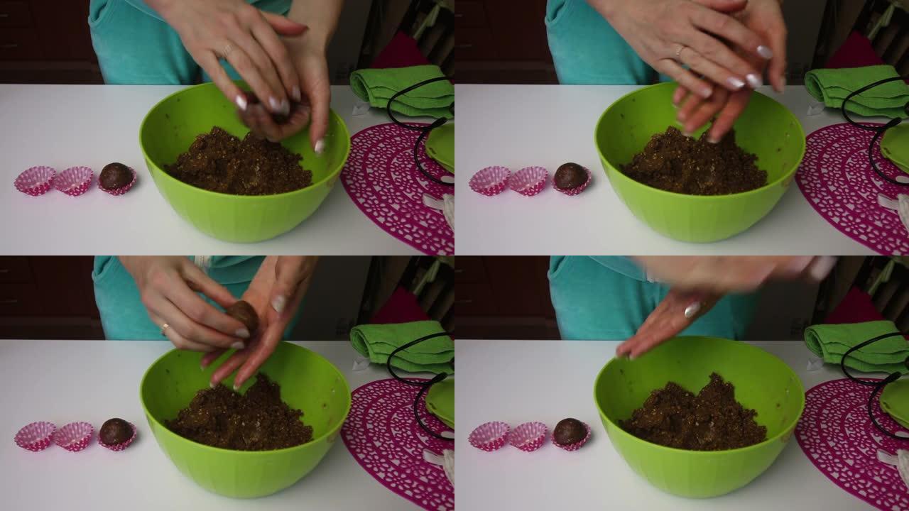 一名妇女用手从饼干和可可的面包屑制成的团块中滚动球，并添加黄油。制作土豆饼干的空白。