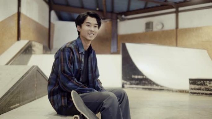 在滑板公园里一个年轻微笑的日本男滑板手的肖像 (慢动作)