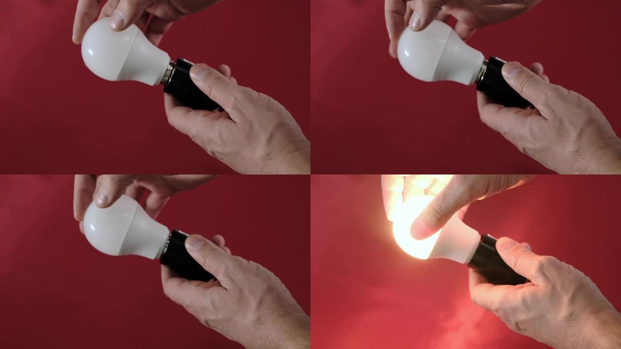 男性双手扭动白色桌子上的节电灯泡。特写。