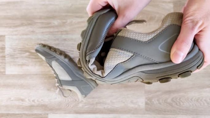 白手挤压灰色运动鞋。测试橡胶鞋底的柔韧性