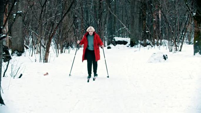 一个穿着红色羽绒服的年轻金发女子在森林里滑雪行走