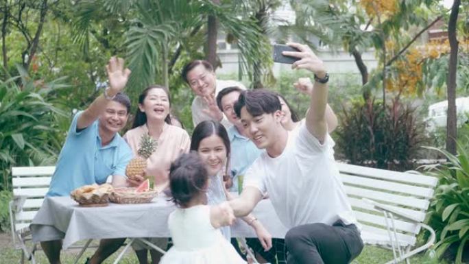 视频会议上的多代东南亚家庭，同时在家享受派对户外花园