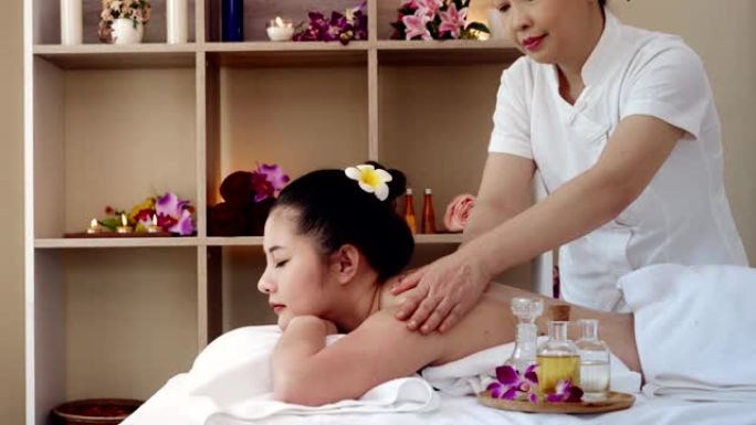 亚洲妇女放松，同时接受一个专业的按摩治疗美容和健康。按摩师用油按摩亚洲女性的身体