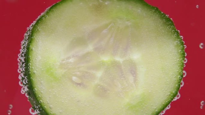 气泡和一滴水在装有黄瓜片和冰的玻璃杯的侧面。关闭。新鲜蔬菜宏观选择性聚焦