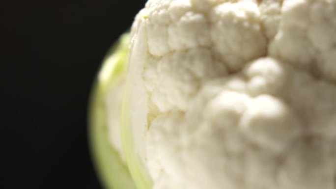 新鲜的生白色花椰菜头在黑色背景上旋转特写。