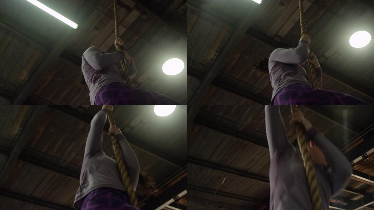女人在工业风格的健身房中下降攀岩绳的慢动作