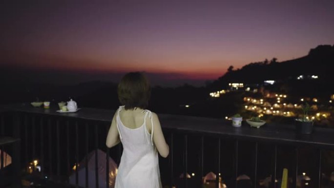 女人坐在山顶上放松，晚上欣赏壮丽的景色