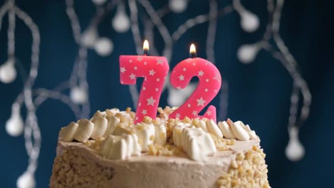 蓝色背景上有72号粉色蜡烛的生日蛋糕。蜡烛吹灭了。慢动作和特写视图