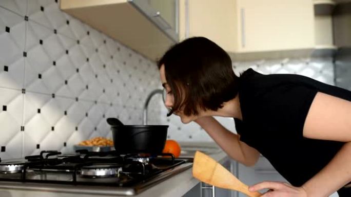 年轻女子素食主义者站在厨房的炉子上，在锅里煮东西