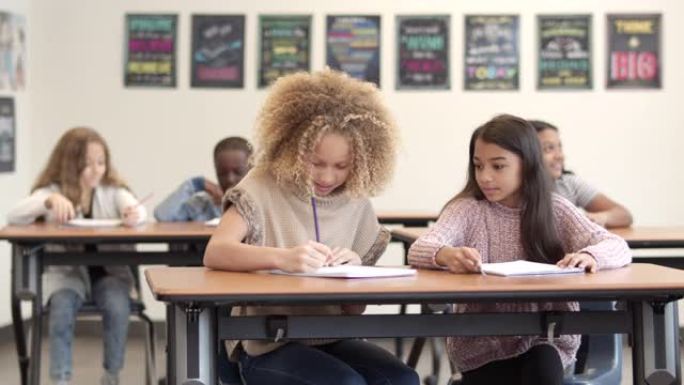 两个年轻女孩在课堂上分享笔记的慢动作平移镜头