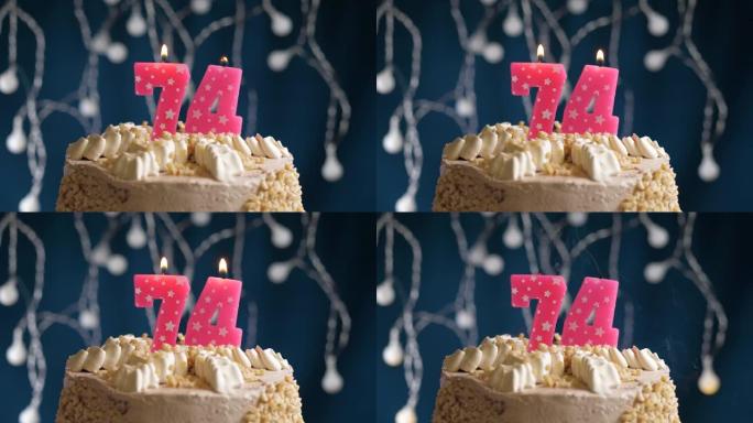 蓝色背景上有74号粉色蜡烛的生日蛋糕。蜡烛吹灭了。慢动作和特写视图
