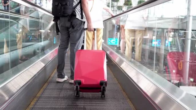 在机场的自动扶梯上带着旅行包的人。