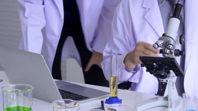 科学家在科学实验室中使用笔记本电脑搜索医学研究信息。科学家使用显微镜来测试和编写测试结果。实验室里有