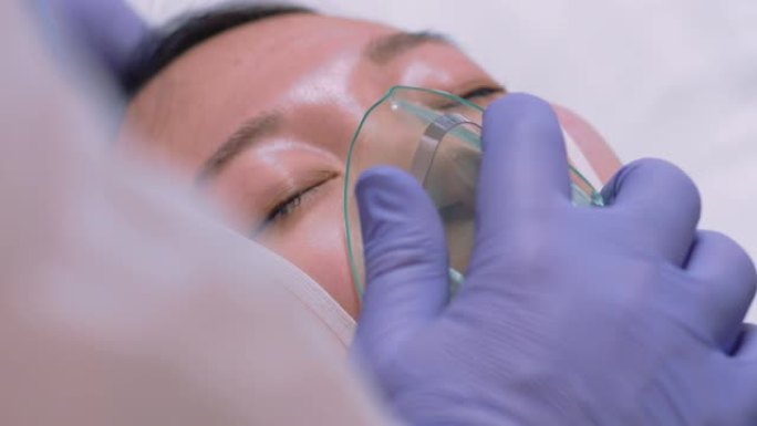 穿着防护服的医生给患有冠状病毒的病人戴上氧气面罩 -- 近距离慢动作镜头